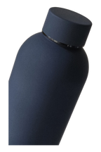 The navy bottle tilted, close up on the soft-touch matte finish and the screw cap