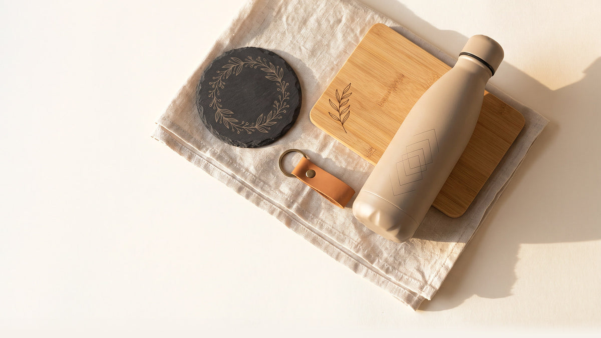 Laser-engraved gifts on linen - a slate coaster, a bamboo board, an engraved bottle and a leather keyring