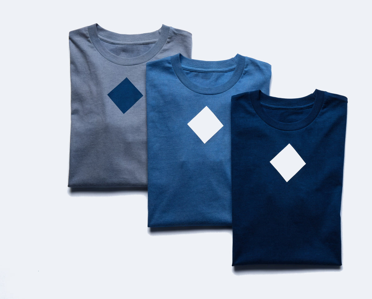 Three folded t-shirts, each screen printed with the same plain diamond