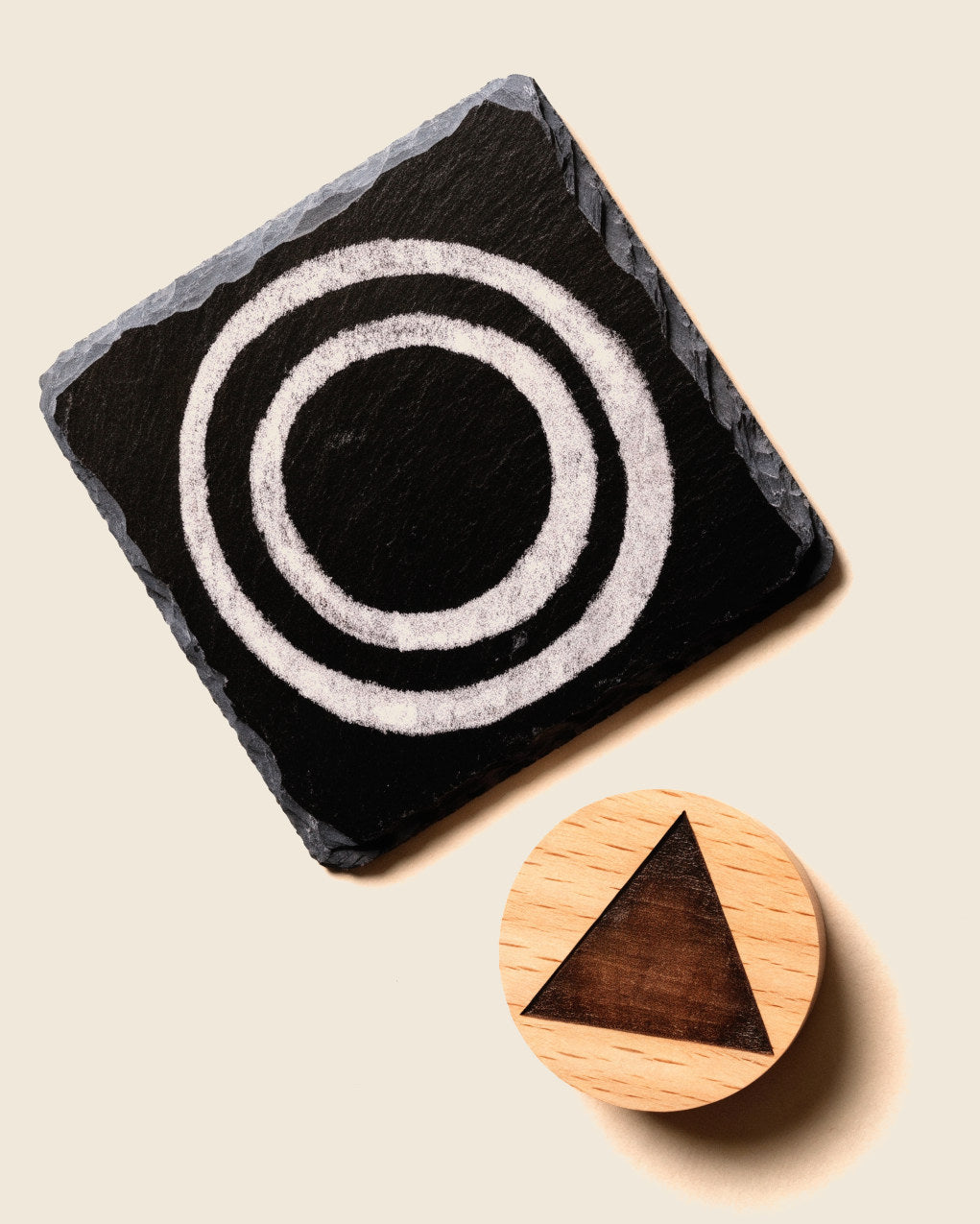 An engraved slate coaster, an oak disc and a tumbler, each marked differently