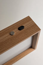 Close up of the top of the frame: a round metal touch button and a USB-C charging port set into the wood