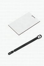 A blank white sublimation bag tag with its black strap beside it
