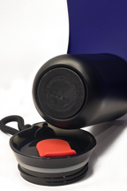 The cup on its side showing its grippy black base, with the lid lying open in front of it